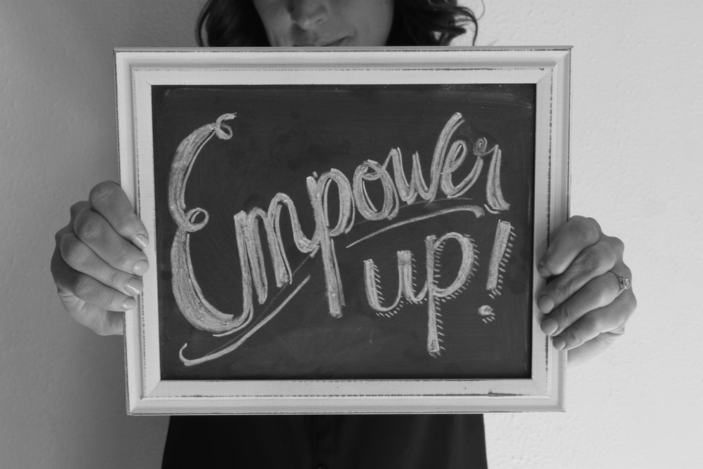 Stacy Davison, creator of the Personal Pep Talk strategy card decks, holding a chalkboard with a hand lettered message that says Empower up!