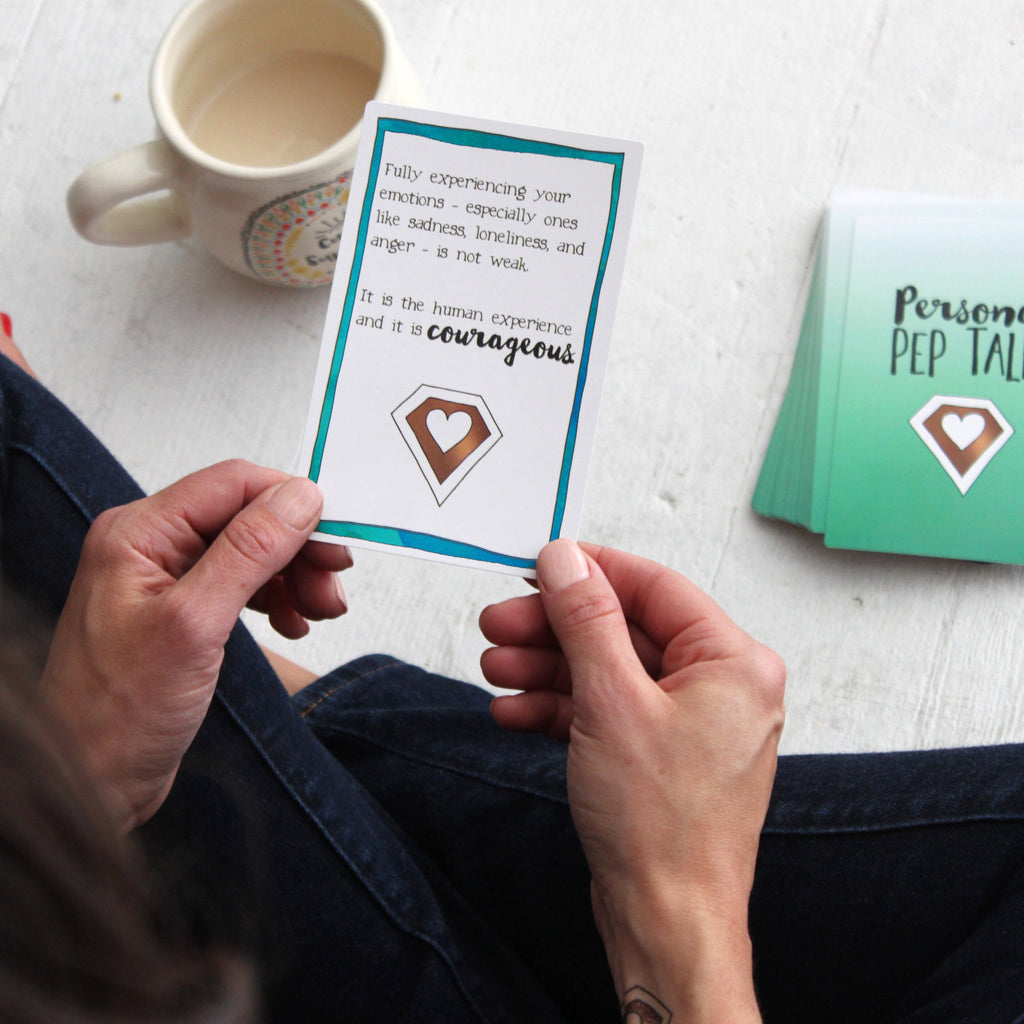 A woman reading a strategy card about emotions from the Personal Pep Talk card deck
